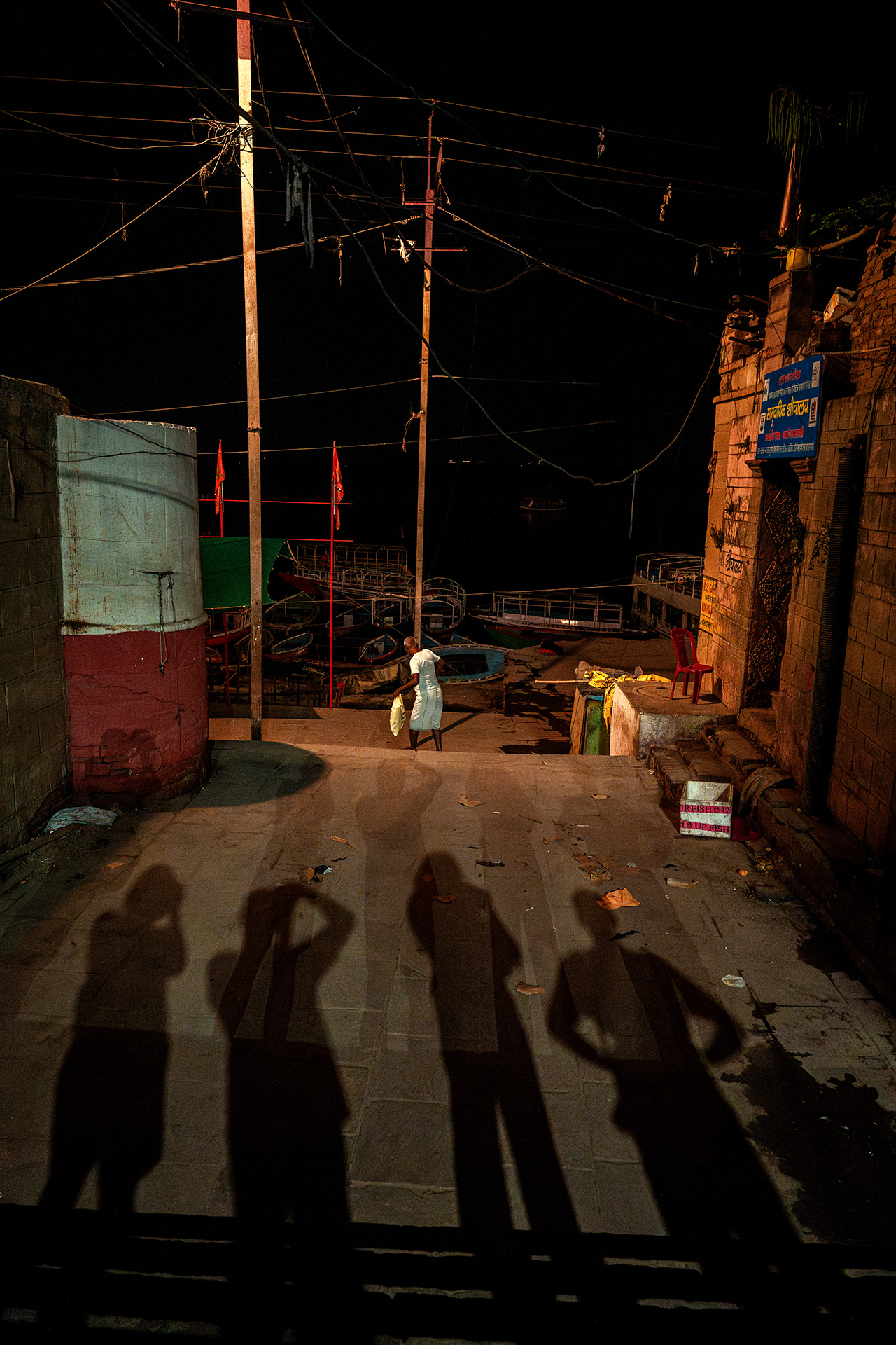 Cienie grupy fotografujących na nocnej ulicy w Varanasi