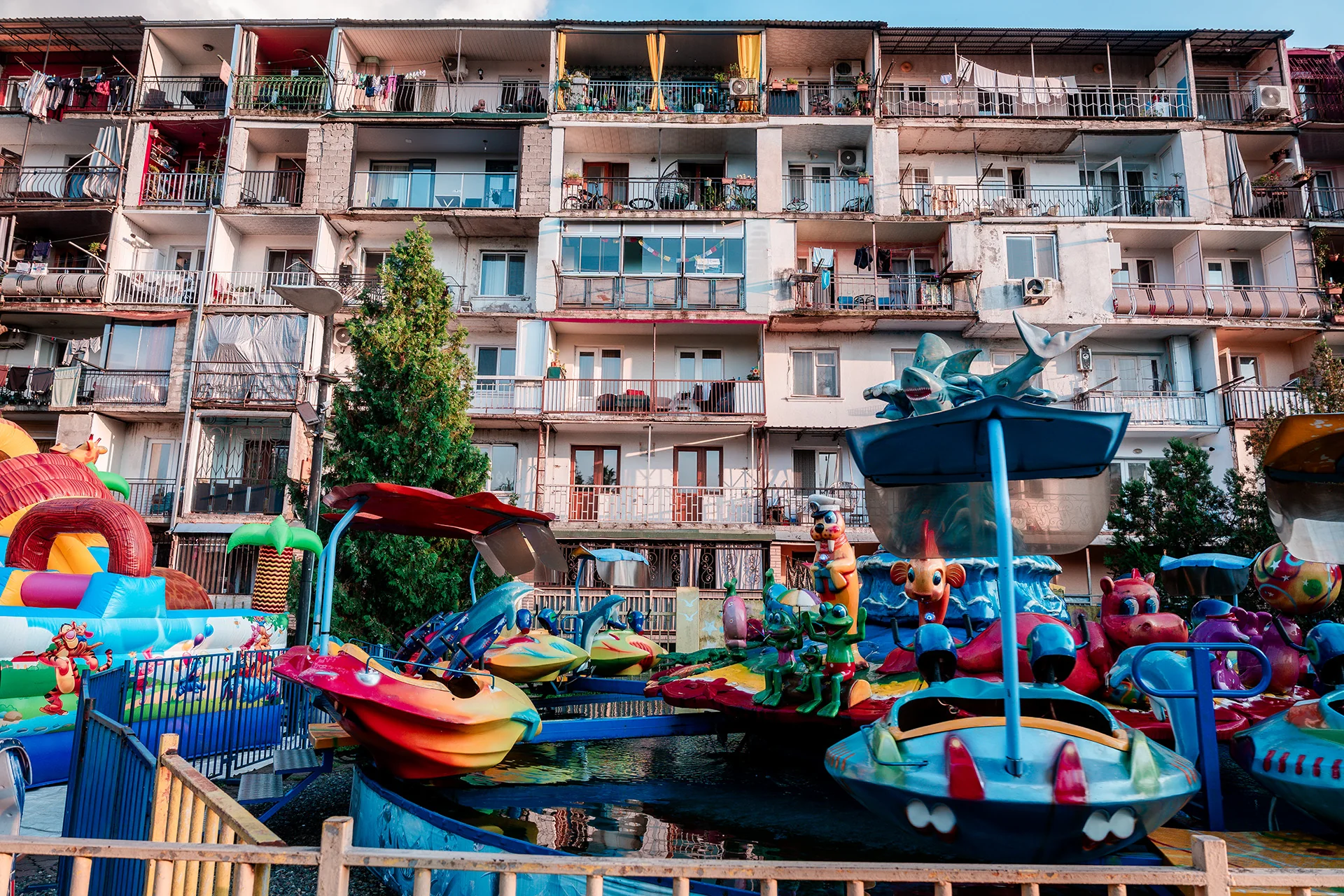 Kolorowe karuzele lunaparku pod blokiem mieszkalnym w Batumi