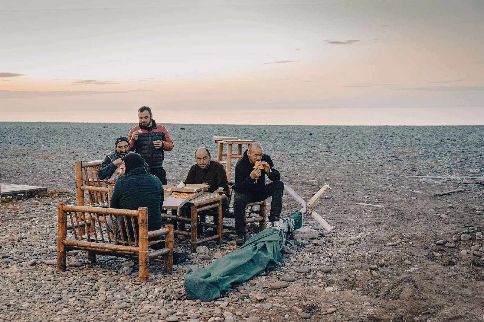 Batumi, mężczyźni przy stole na kamienistej plaży o&nbsp;zmierzchu